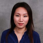 A headshot of Shuhui Grace Yang wearing a dark blue top, in front of a gray background