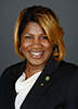 A headshot of Tasha Jackson wearing a dark blazer over a white shirt, in front of a dark gray background