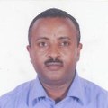 A headshot of Solomon Zewde wearing a blue button-down shirt in front of a white background