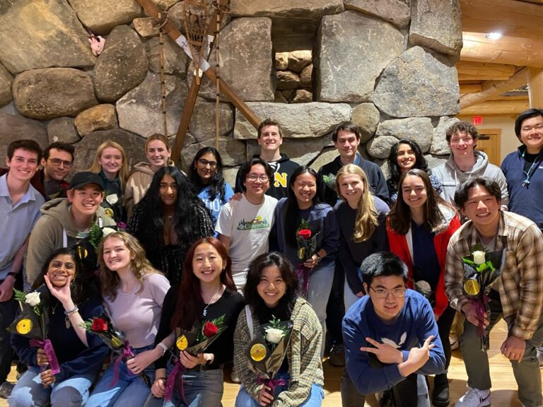 Smiling group photo of Kaylie — in a navy sweater and long blond hair — with 21 of her diverse Dartmouth DALI Lab co-workers