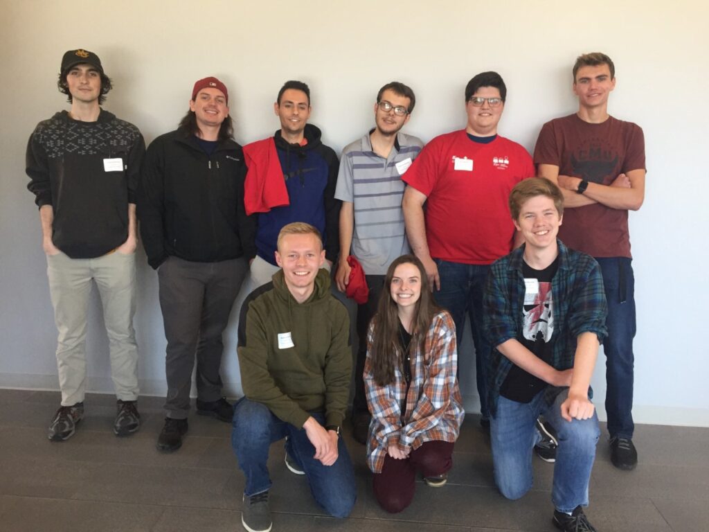 Color group photo of Bryn — second person kneeling on the right in a plaid button-down — amongst nine CS club members at ICPC North America