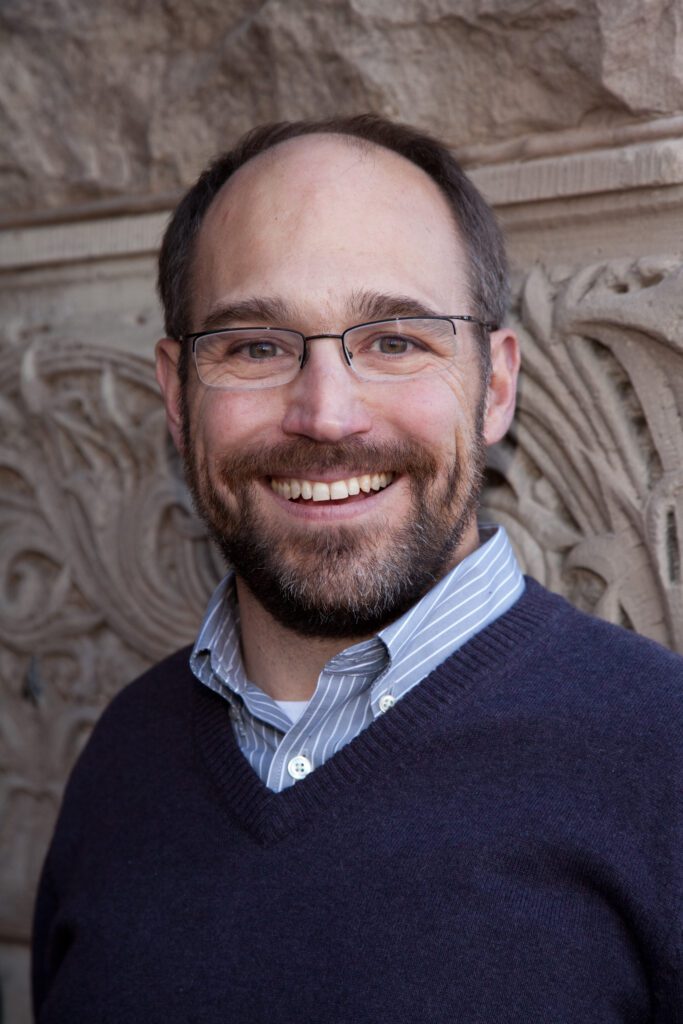 A headshot of Ken Anderson smiling at the camera